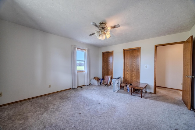 bedroom featuring baseboards, carpet flooring, a textured ceiling, and two closets