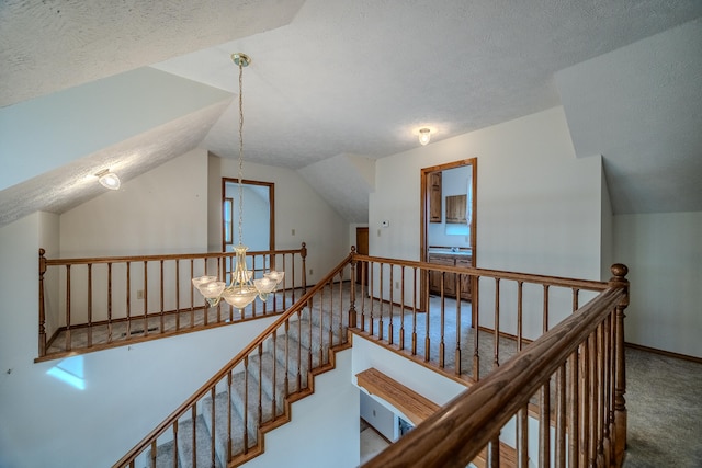 staircase featuring lofted ceiling, a chandelier, a textured ceiling, and carpet flooring