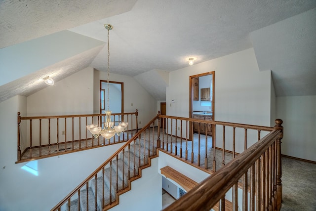 stairs featuring carpet floors, a textured ceiling, a chandelier, and lofted ceiling