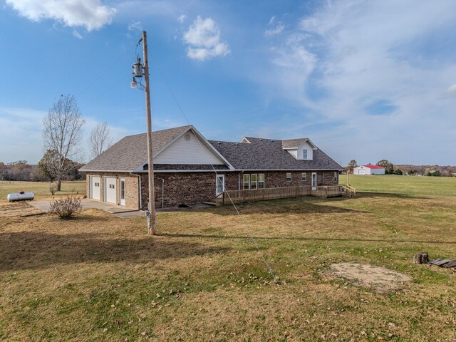 back of house featuring a garage, a wooden deck, and a yard