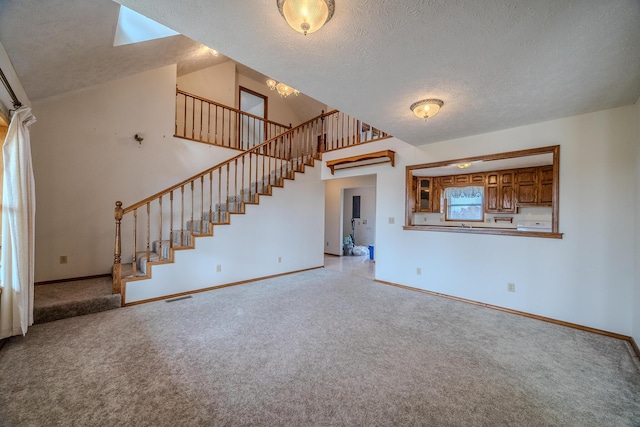 unfurnished living room featuring stairway, a textured ceiling, and carpet