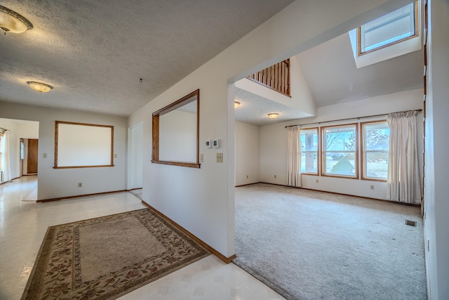 interior space featuring vaulted ceiling with skylight, light carpet, and a textured ceiling