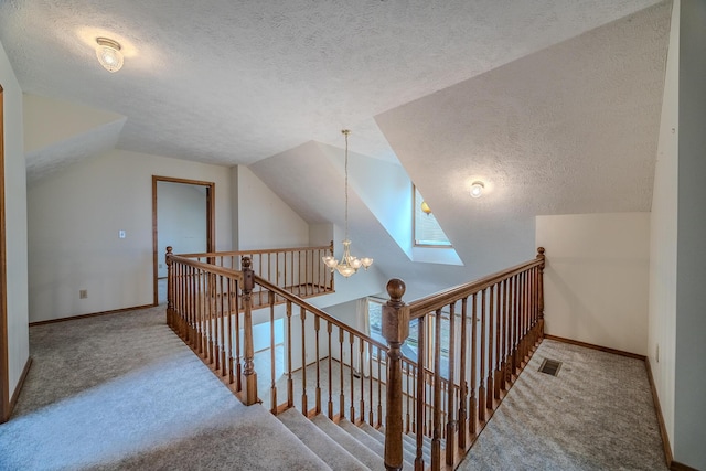 stairs featuring visible vents, carpet flooring, a textured ceiling, and lofted ceiling