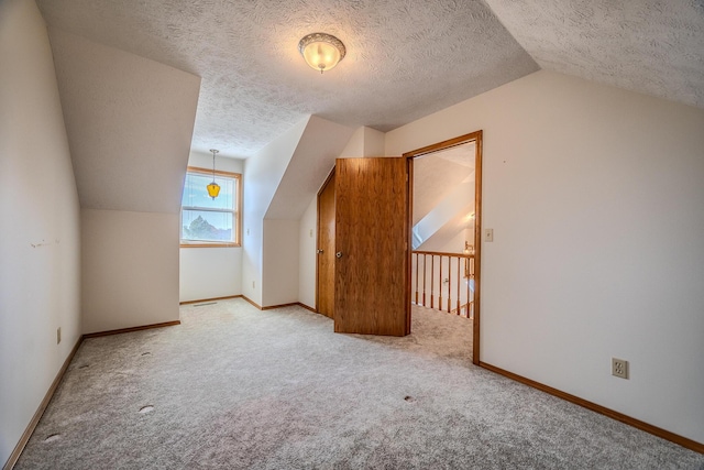 additional living space featuring carpet floors, baseboards, vaulted ceiling, and a textured ceiling