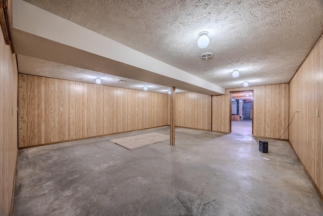 basement featuring a textured ceiling and wood walls