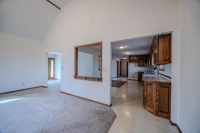 interior space featuring light countertops, high vaulted ceiling, and baseboards