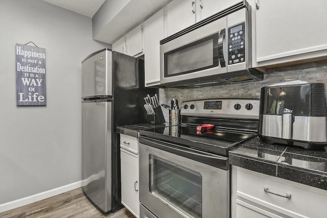 kitchen featuring light hardwood / wood-style floors, decorative backsplash, white cabinets, and stainless steel appliances