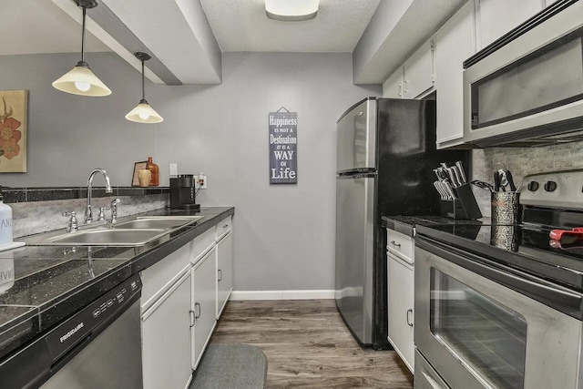 kitchen with dark hardwood / wood-style floors, sink, decorative light fixtures, white cabinetry, and appliances with stainless steel finishes