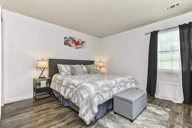 bedroom featuring a textured ceiling and dark hardwood / wood-style flooring