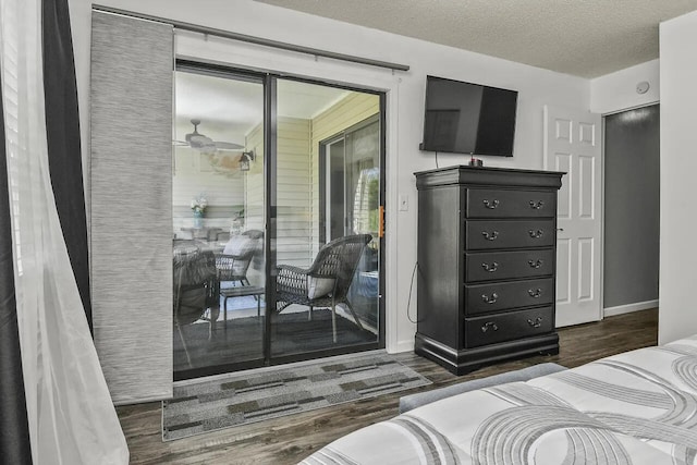 bedroom with access to outside, dark hardwood / wood-style floors, and a textured ceiling