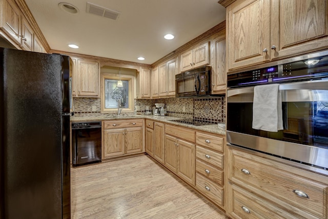 kitchen with decorative backsplash, light stone counters, black appliances, light hardwood / wood-style floors, and sink