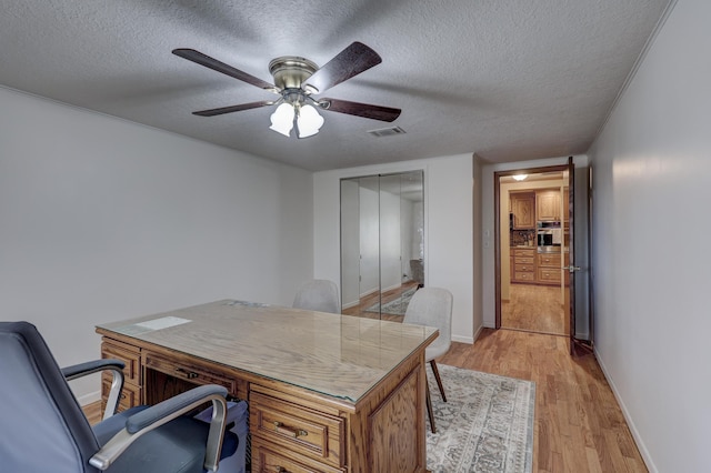 office with a textured ceiling, light hardwood / wood-style floors, and ceiling fan