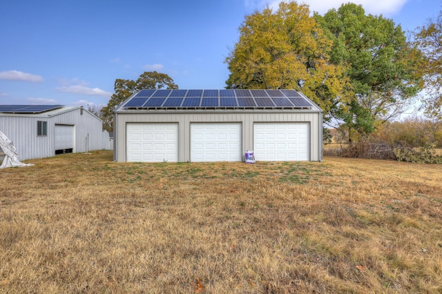 garage featuring solar panels and a lawn