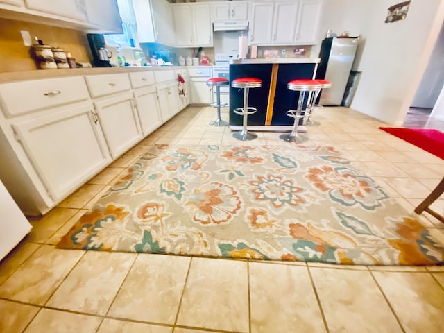 kitchen featuring white cabinetry, light tile patterned flooring, and a breakfast bar area