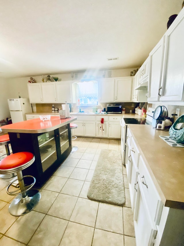 kitchen with exhaust hood, a center island, light tile patterned floors, white cabinets, and white appliances