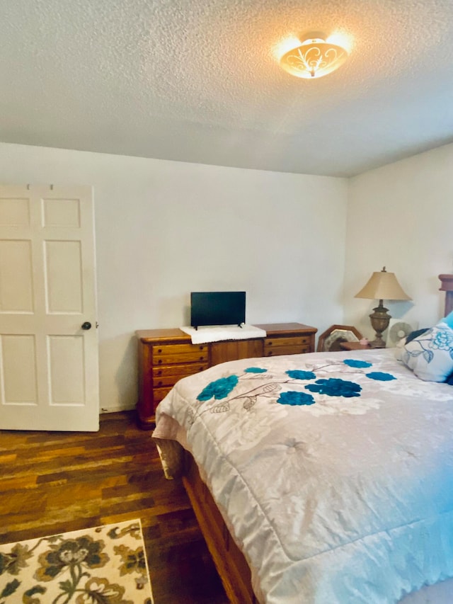 bedroom with a textured ceiling and dark hardwood / wood-style flooring