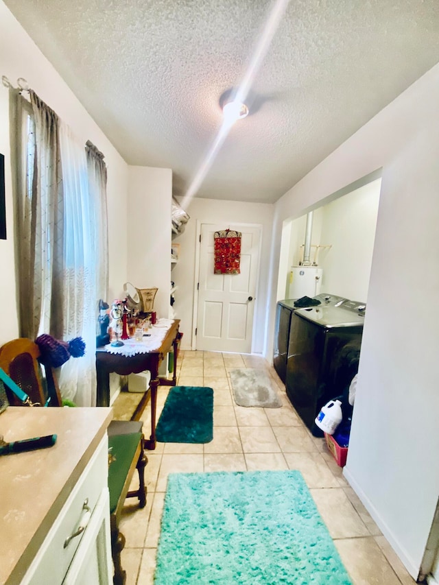 tiled entrance foyer with water heater, a textured ceiling, and separate washer and dryer