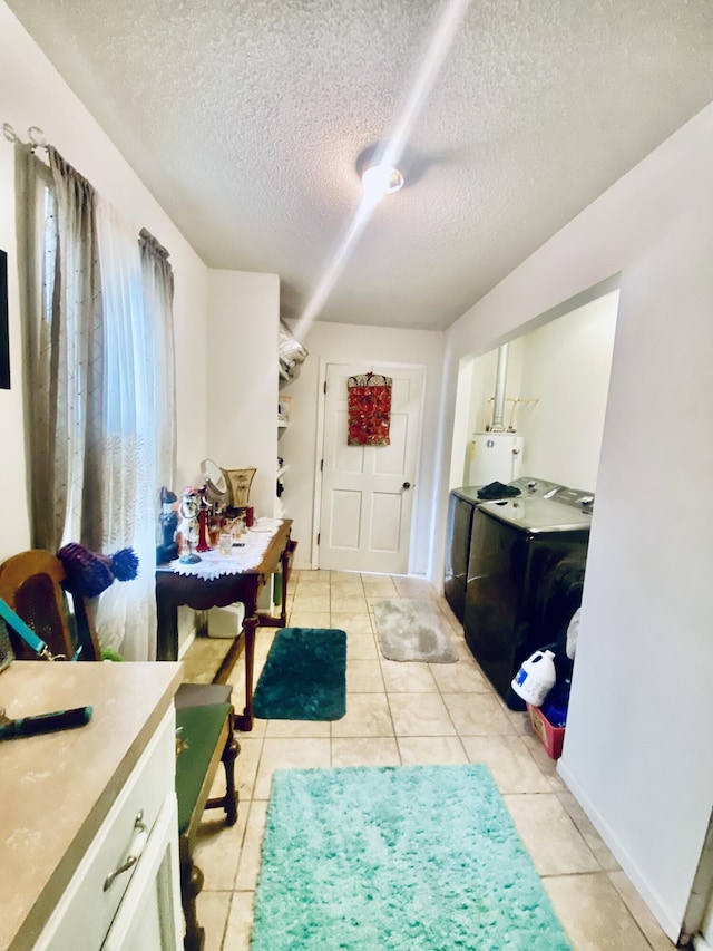 entryway with a textured ceiling, light tile patterned floors, gas water heater, and washing machine and clothes dryer