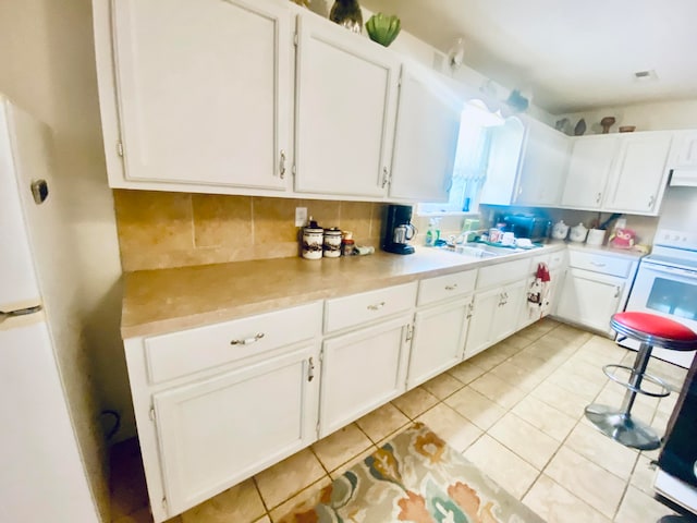 kitchen with backsplash, light tile patterned floors, white cabinetry, sink, and white refrigerator