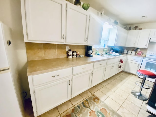 kitchen with white appliances, white cabinetry, light tile patterned floors, and light countertops