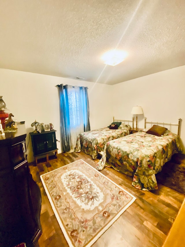 bedroom with dark wood-type flooring and a textured ceiling