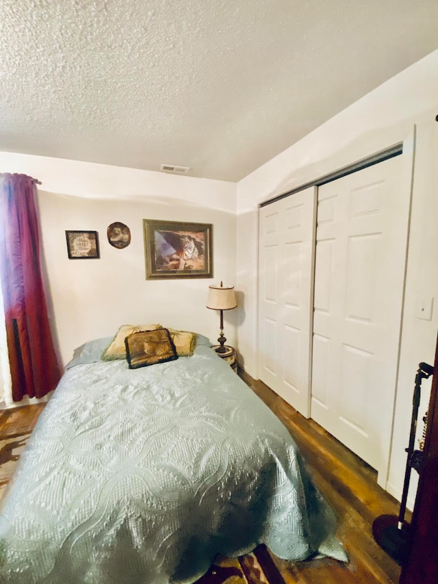 bedroom with a closet, dark hardwood / wood-style floors, and a textured ceiling