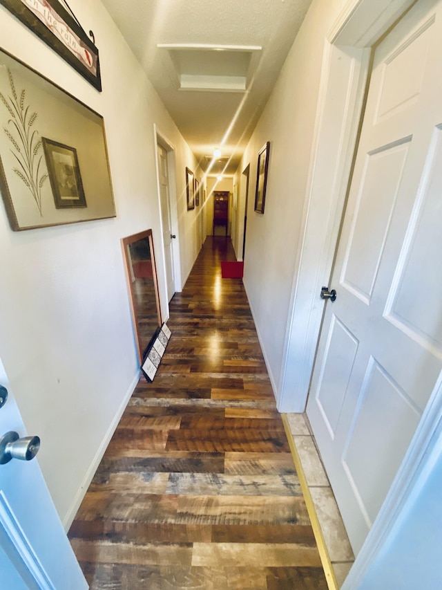 corridor featuring baseboards, attic access, and wood finished floors