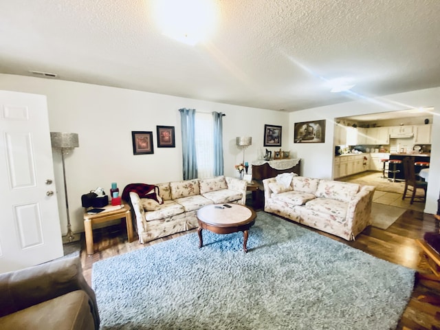 living area featuring visible vents, a textured ceiling, and light wood finished floors