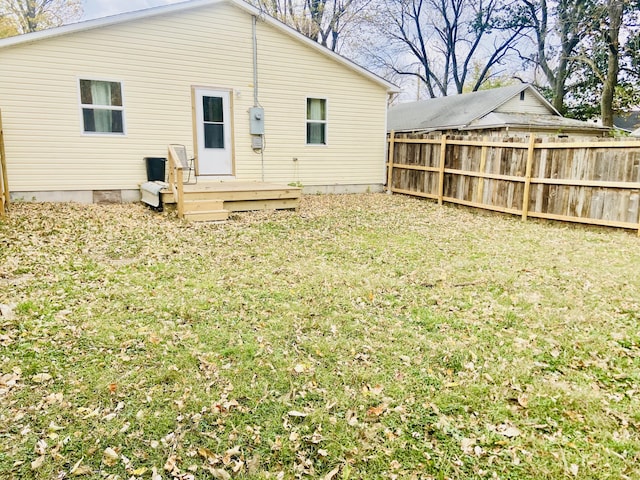 back of property with fence, a lawn, and a deck