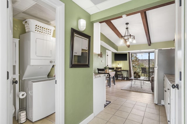 clothes washing area with an inviting chandelier, stacked washer and clothes dryer, and light wood-type flooring