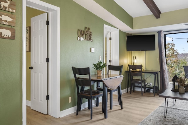 dining room with beam ceiling and hardwood / wood-style floors