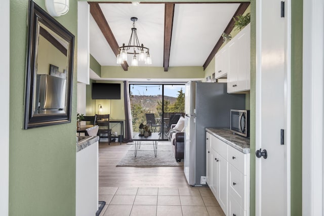 kitchen featuring white cabinetry, beamed ceiling, a notable chandelier, decorative light fixtures, and light wood-type flooring