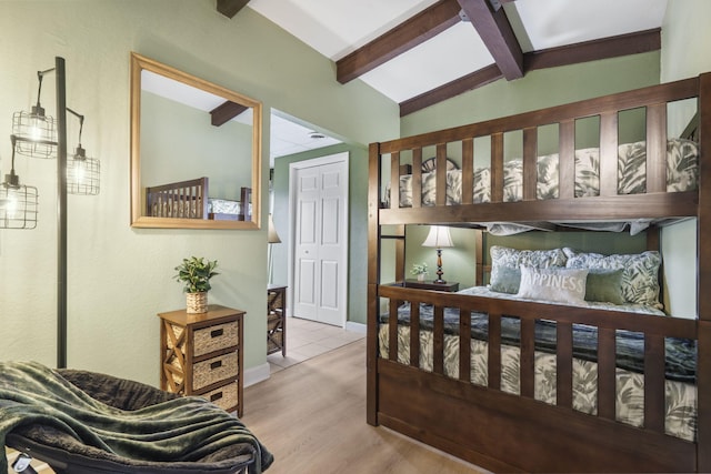 bedroom with lofted ceiling with beams, light hardwood / wood-style flooring, and a closet