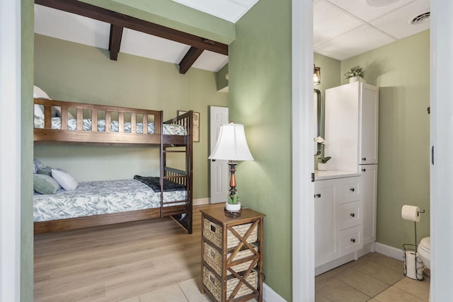 bedroom with light hardwood / wood-style floors and beam ceiling