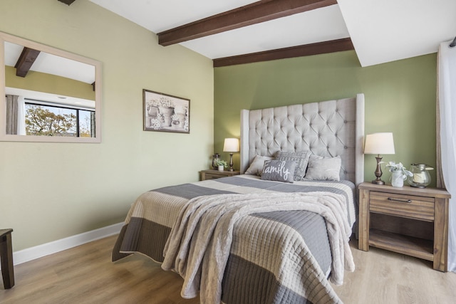 bedroom with beamed ceiling and light hardwood / wood-style floors