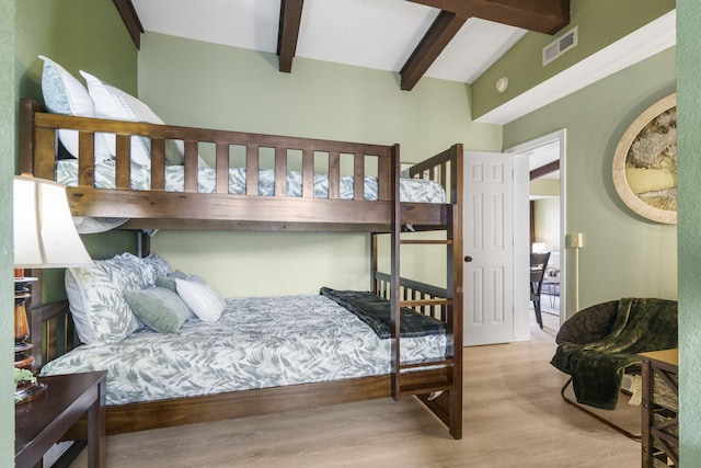 bedroom featuring vaulted ceiling with beams and light wood-type flooring