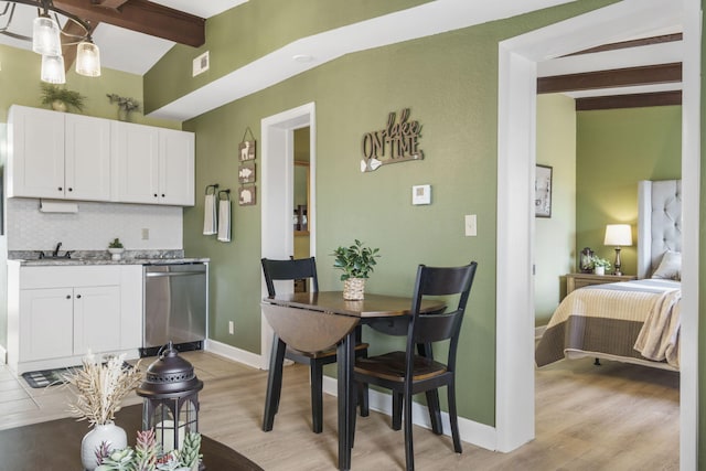 dining room with vaulted ceiling with beams, sink, and light hardwood / wood-style floors