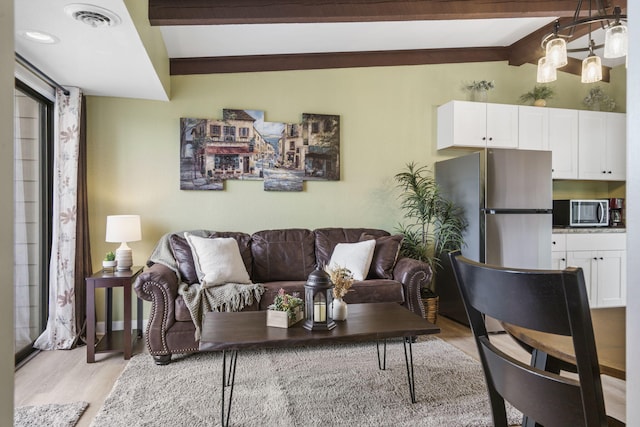 living room with lofted ceiling with beams and light hardwood / wood-style floors