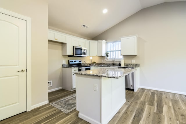 kitchen with lofted ceiling, a kitchen island, white cabinetry, light hardwood / wood-style floors, and stainless steel appliances