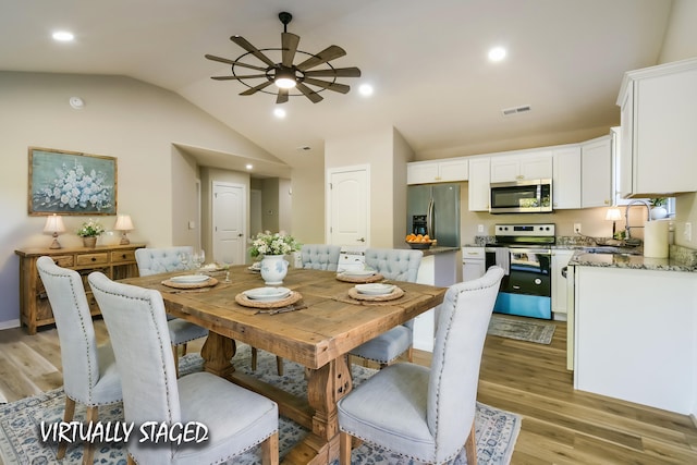 dining space with sink, light hardwood / wood-style floors, vaulted ceiling, and ceiling fan