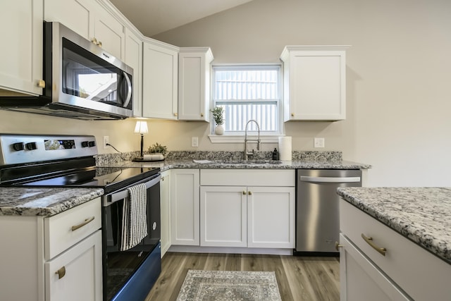 kitchen featuring light stone countertops, white cabinets, light hardwood / wood-style flooring, and stainless steel appliances