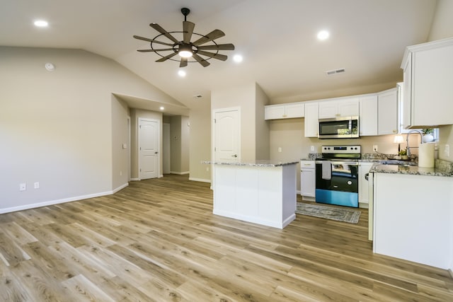 kitchen featuring a center island, white cabinetry, stainless steel appliances, and lofted ceiling