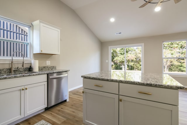 kitchen featuring light stone countertops, vaulted ceiling, light hardwood / wood-style flooring, dishwasher, and sink