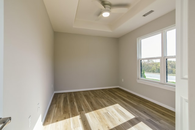 empty room featuring ceiling fan, a tray ceiling, and hardwood / wood-style floors