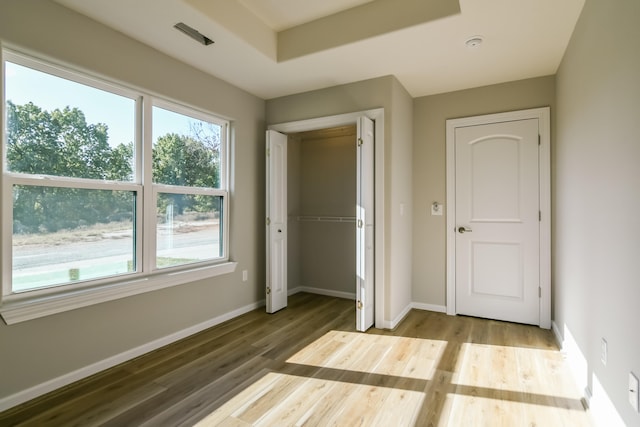 unfurnished bedroom with a closet, multiple windows, and hardwood / wood-style flooring