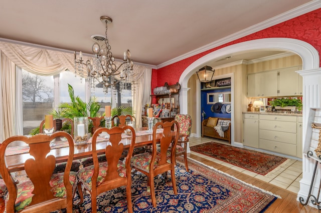 dining room with light hardwood / wood-style floors, an inviting chandelier, and ornamental molding