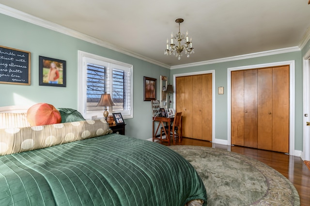 bedroom featuring ornamental molding, a chandelier, multiple closets, and dark hardwood / wood-style flooring