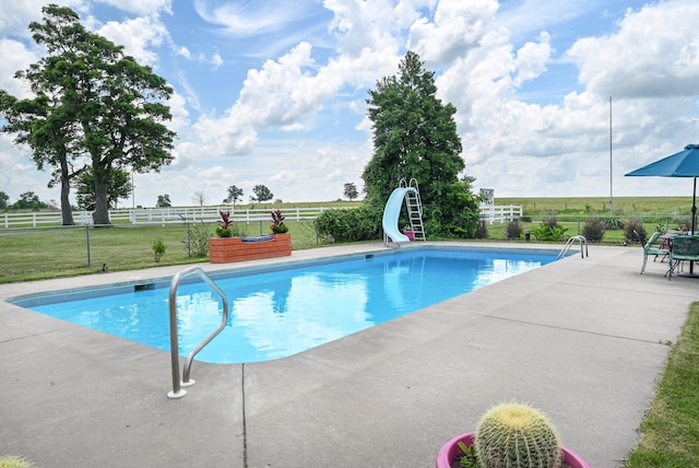 view of pool featuring a water slide, a lawn, and a patio area