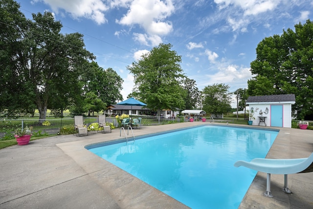 view of pool featuring a patio, a water slide, and an outdoor structure