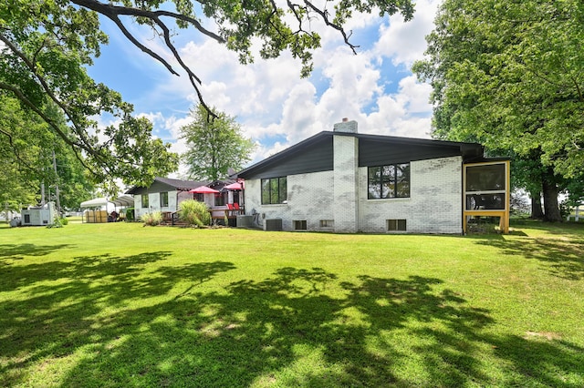15778 Lawrence Unit 2130, Mount Vernon, MO 65712 - rear view of property featuring brick siding, a chimney, a lawn, a sunroom, and cooling unit